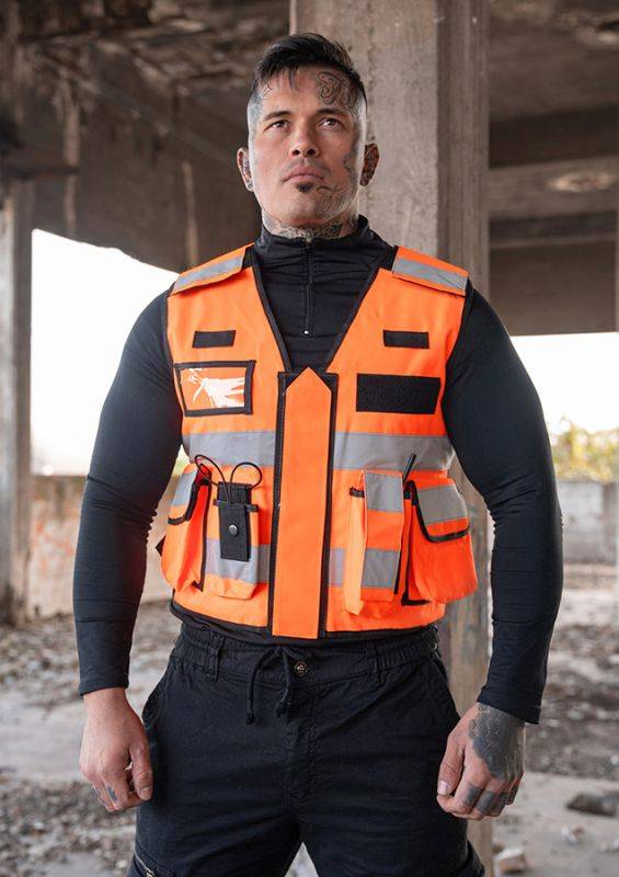 Modell trägt orange Tactical Vest Bonn mit Reflexstreifen und funktionellen Taschen, ideal für Outdoor- und Sicherheitsdienste.