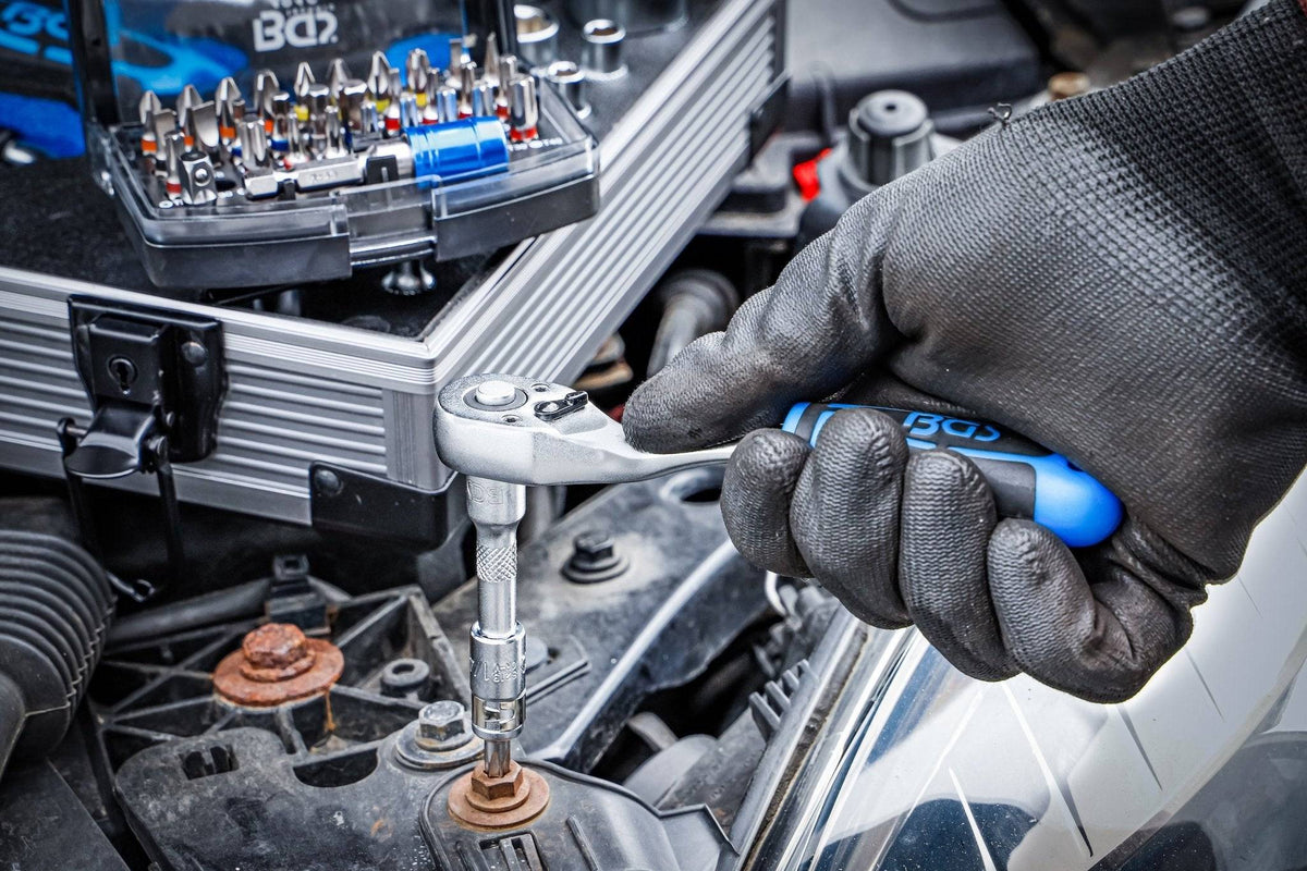 Mechaniker verwendet Ratsche aus dem Universal-Werkzeugkoffer 85-tlg. 11510 by medasi.shop bei der Autoreparatur, ideal für präzises Arbeiten.